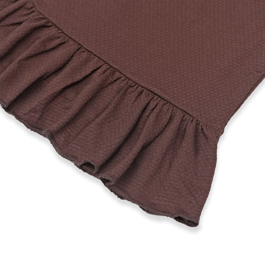Close-up view of a brown baby dress featuring a delicate ruffled hem and textured fabric, highlighting the fine details and soft material.